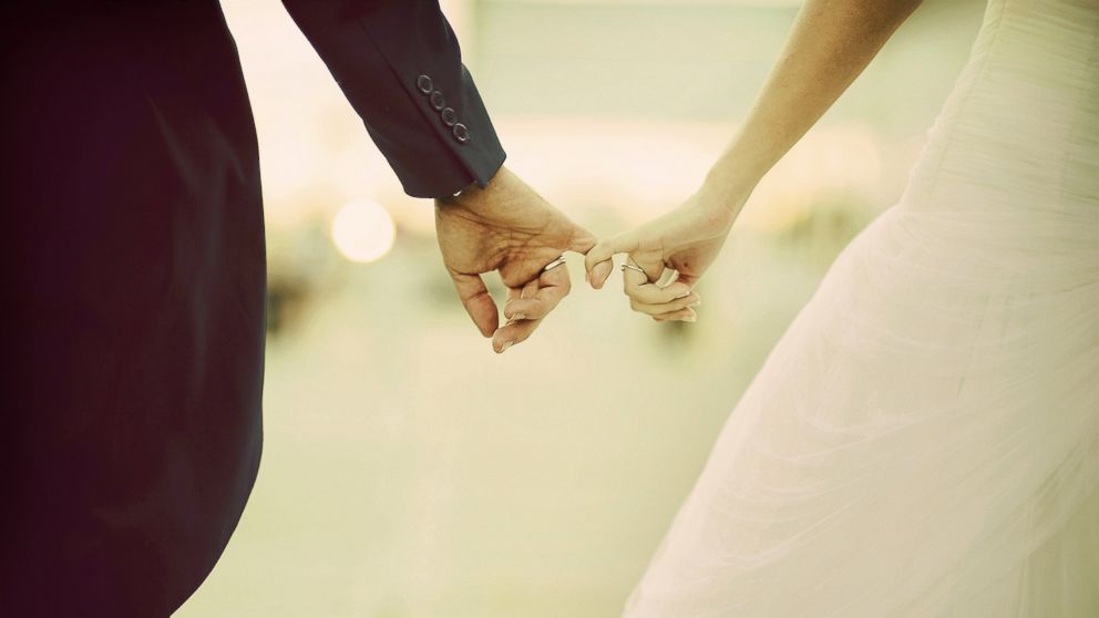 A couple link fingers after their wedding in this stock photo.
