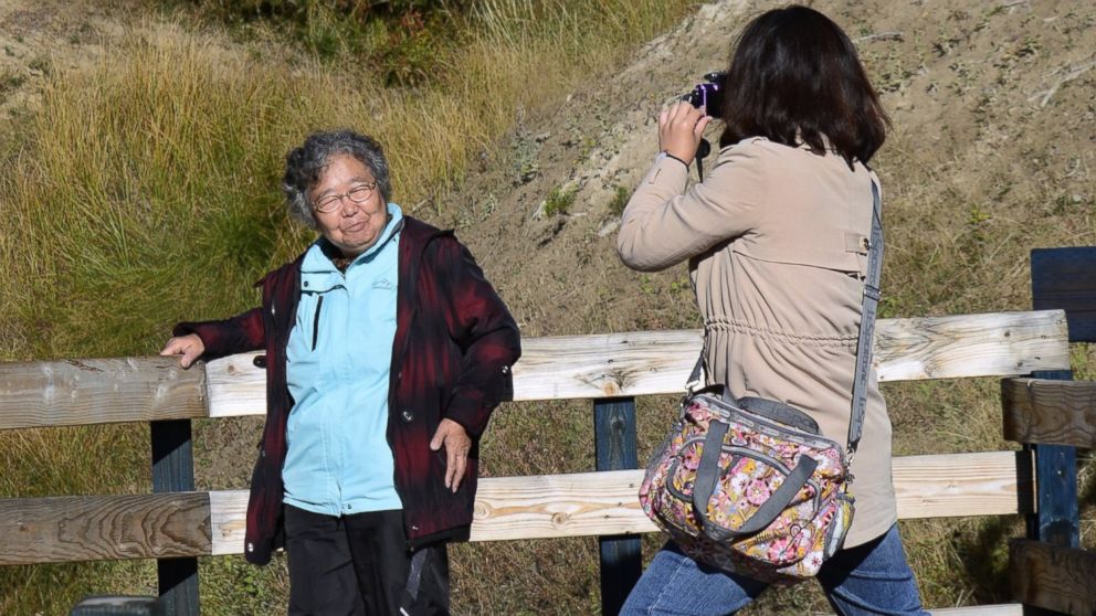 PHOTO: Tourists from China take souvenir photographs on a boardwalk leading to Dragon's Mount Spring, a popular geothermal attraction in Yellowstone National Park in Wyoming on Sept. 25, 2014. 