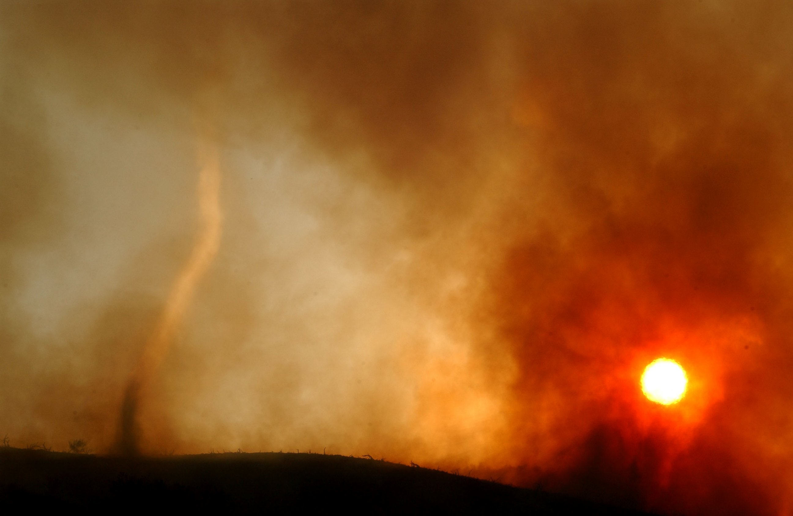 PHOTO: A wildfire-induced tornado of hot ash dances across a ridgetop as the sun sets May 13, 2002 near Rancho Santa Margarita, CA. 