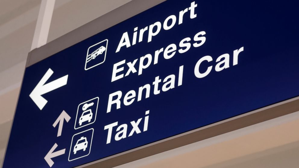 An airport sign with direction arrows for rental cars and taxis.