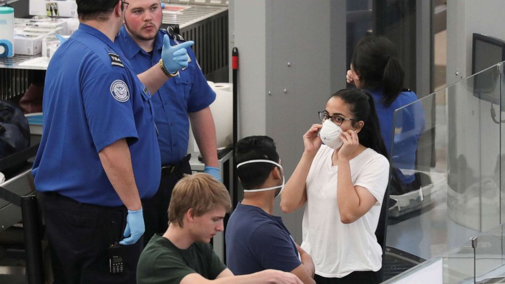 PHOTO: Travelers wear mask as they go through security screening hours before travel restrictions are enacted on flights from Europe entering the U.S. because of concerns of the novel coronavirus at the Denver International Airport on March 13, 2020. 