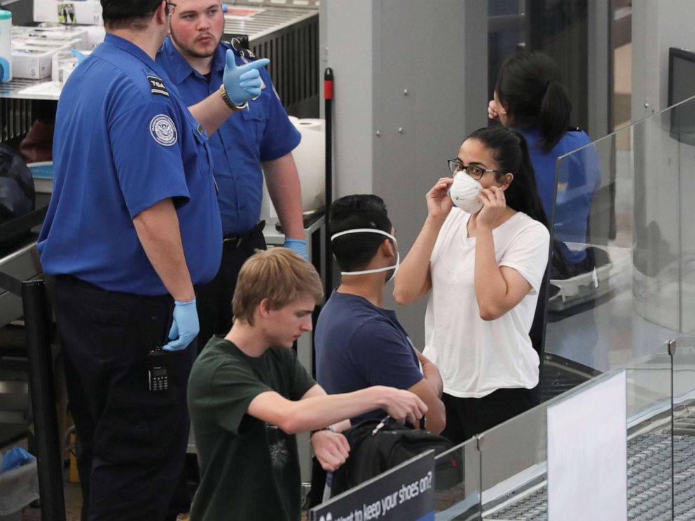 PHOTO: Travelers wear mask as they go through security screening hours before travel restrictions are enacted on flights from Europe entering the U.S. because of concerns of the novel coronavirus at the Denver International Airport on March 13, 2020. 