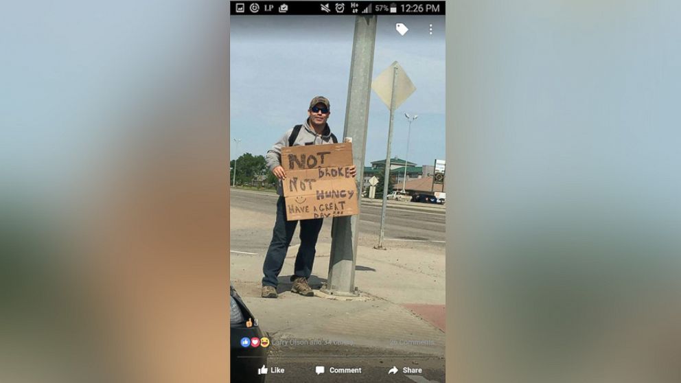 A plainclothes police officer with the Regina Police Service in Saskatchewan holds a sign that says “I’m not broke. I'm not hungry. Have a great day!" as part of a project to observe driver behavior.