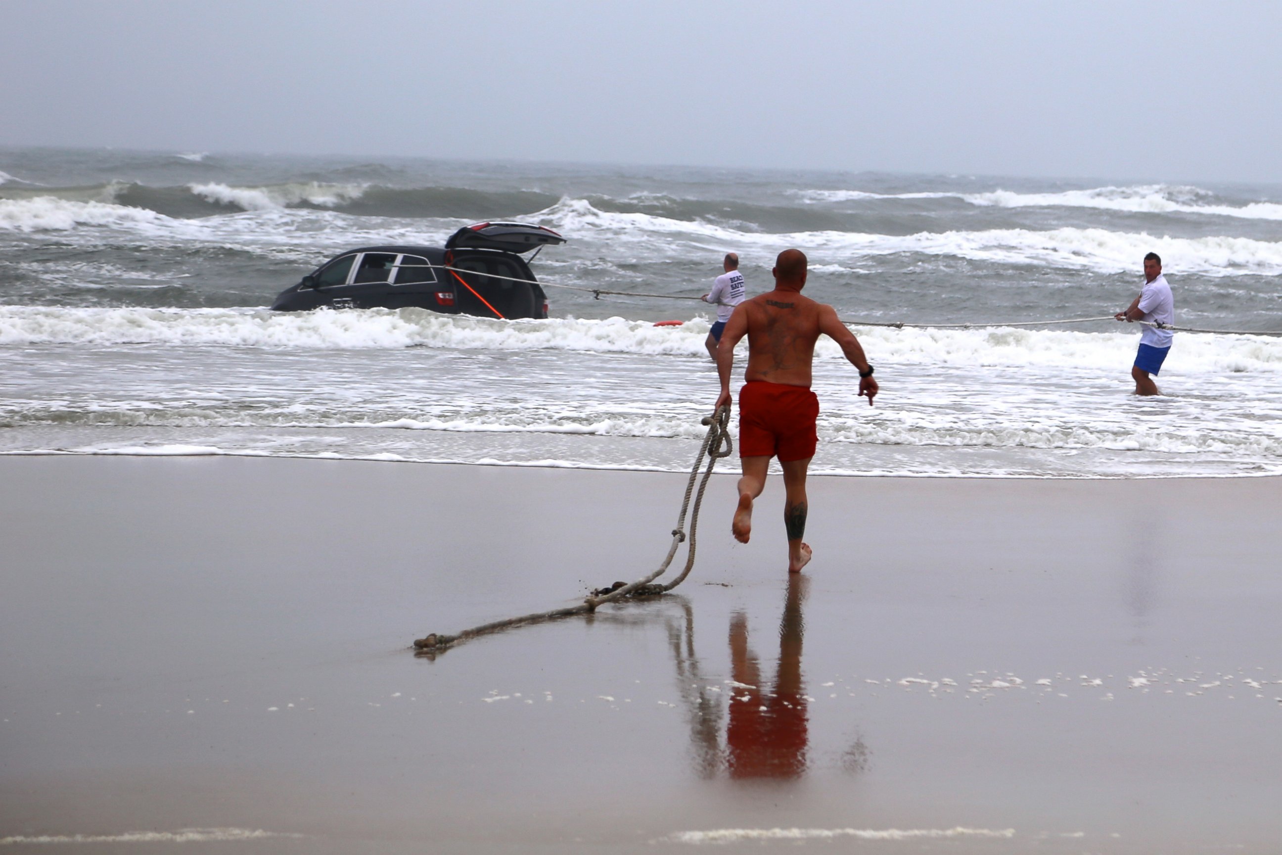 PHOTO: A lifeguard runs in to the ocean to rescue a family  after a mother drives her car in to the ocean, March 5, 2014 in Daytona Beach, Fla.
