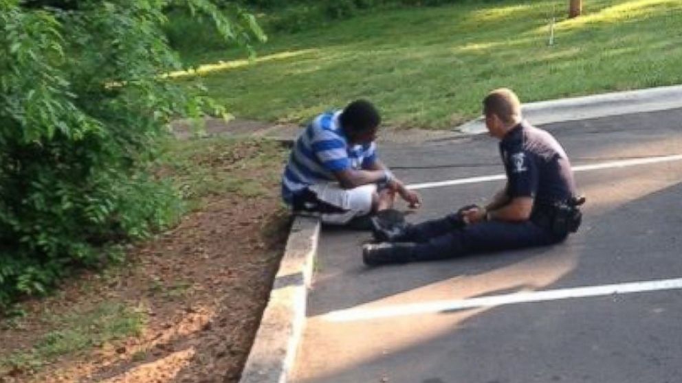 Officer Tim Purdy of the Charlotte-Mecklenburg Police Department soothes a potentially suicidal and autistic teenager in a photo that has gone viral. 