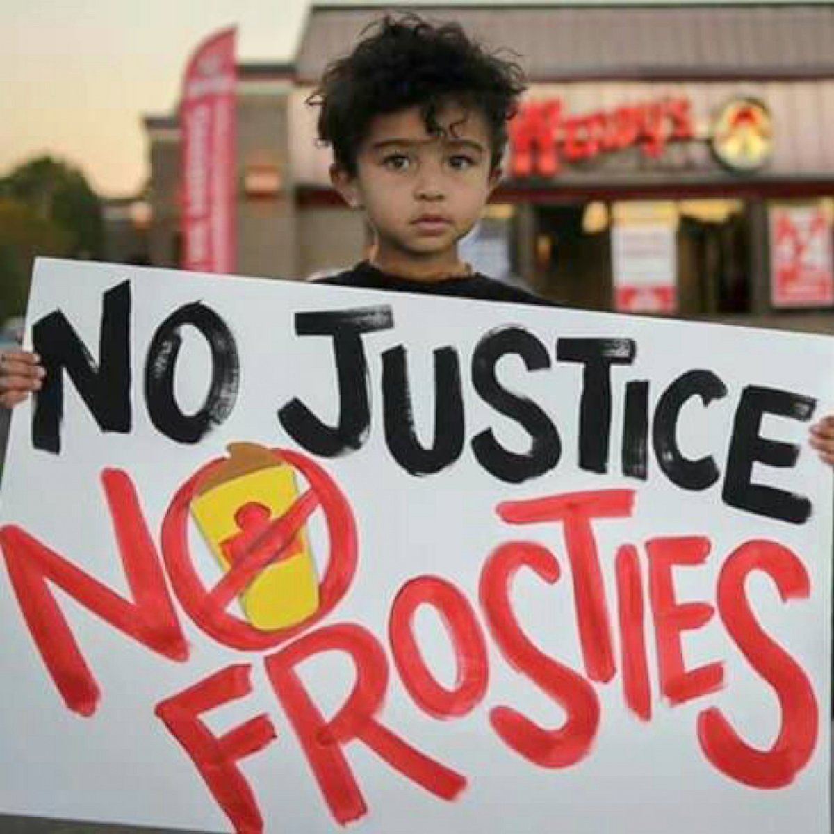 PHOTO: Manige Osowski's younger daughter holds a sign while protesting at the Wendy's that gave her older sister a racist note with her meal.