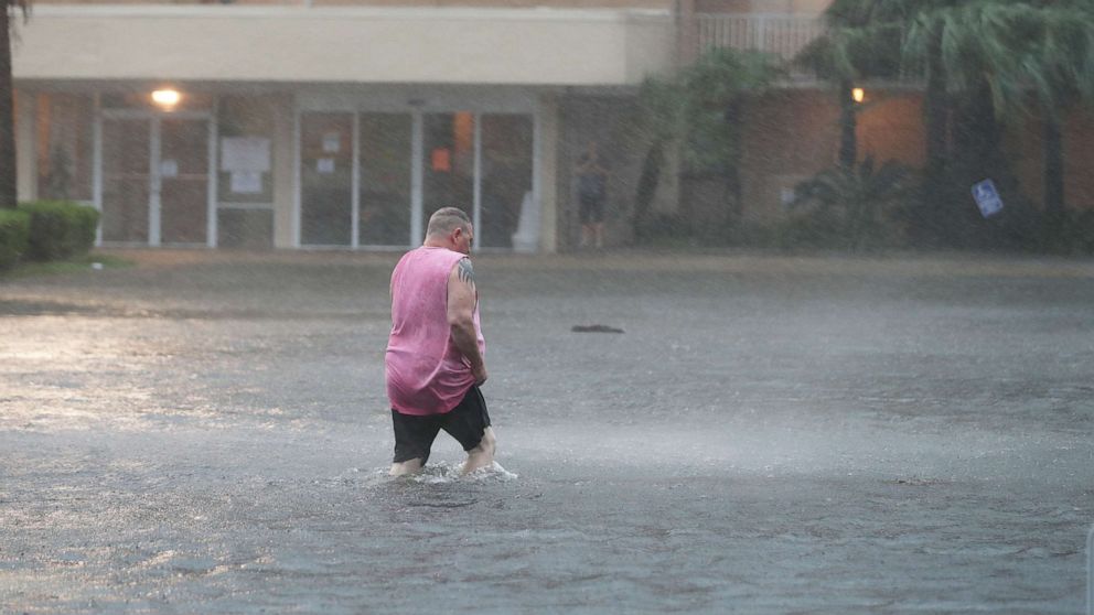 PHOTO: GULF SHORES, ALABAMA - SEPTEMBER 15: A man walks though a flooded parking lot as the outer bands of Hurricane Sally come ashore on September 15, 2020 in Gulf Shores, Alabama. 