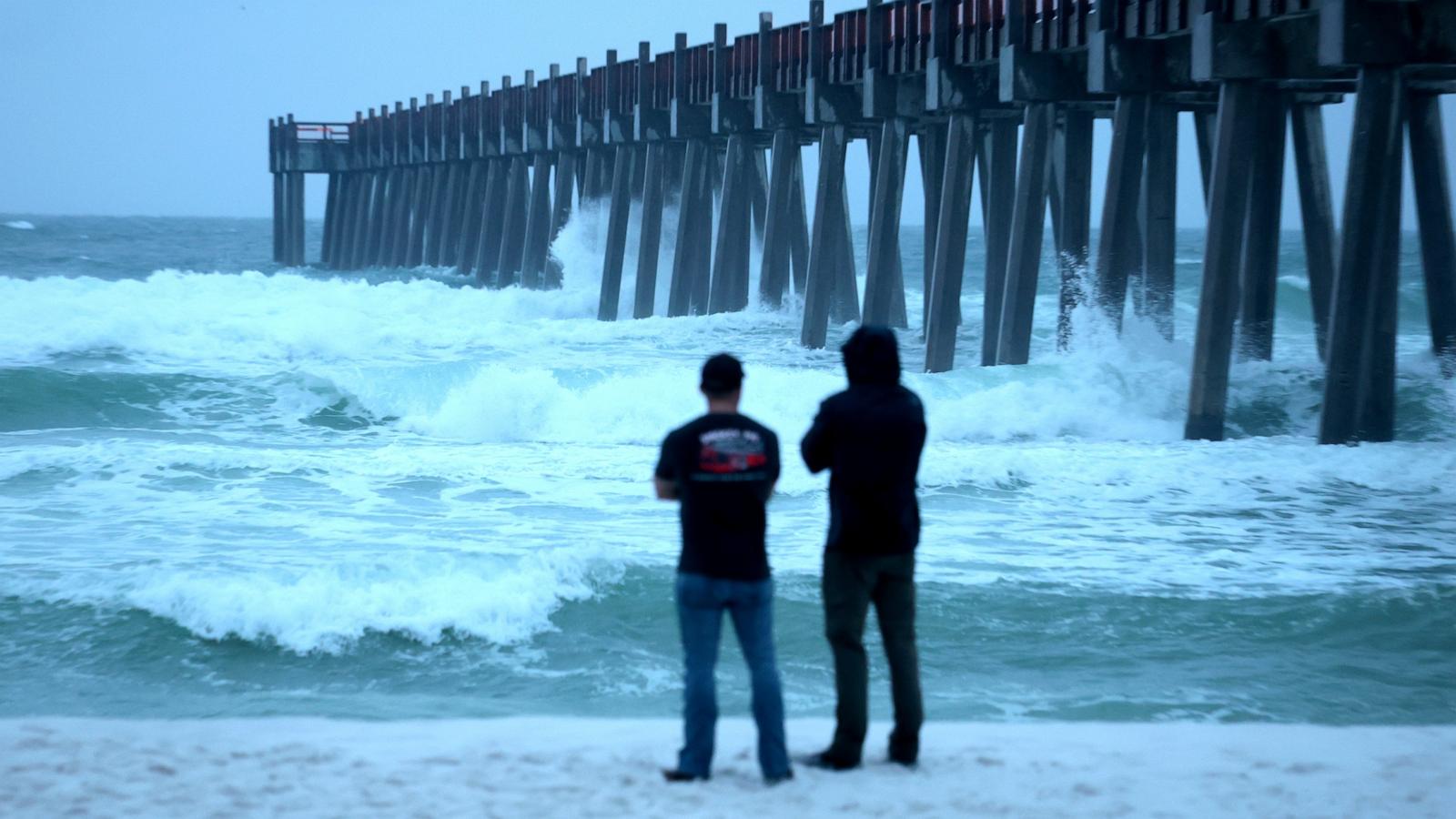 PHOTO: People look out at the waves churning in the ocean as Hurricane Isaias approaches, October 9, 2026, in Pensacola Beach, Florida.