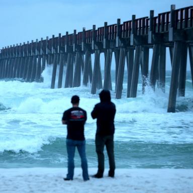 PHOTO: People look out at the waves churning in the ocean as Hurricane Isaias approaches, October 9, 2026, in Pensacola Beach, Florida. 