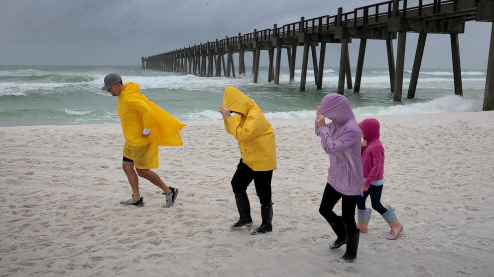PHOTO: People visit the beach as waves churn in the ocean as Hurricane Isaias approaches, October 09, 2026, in Pensacola Beach, Florida.