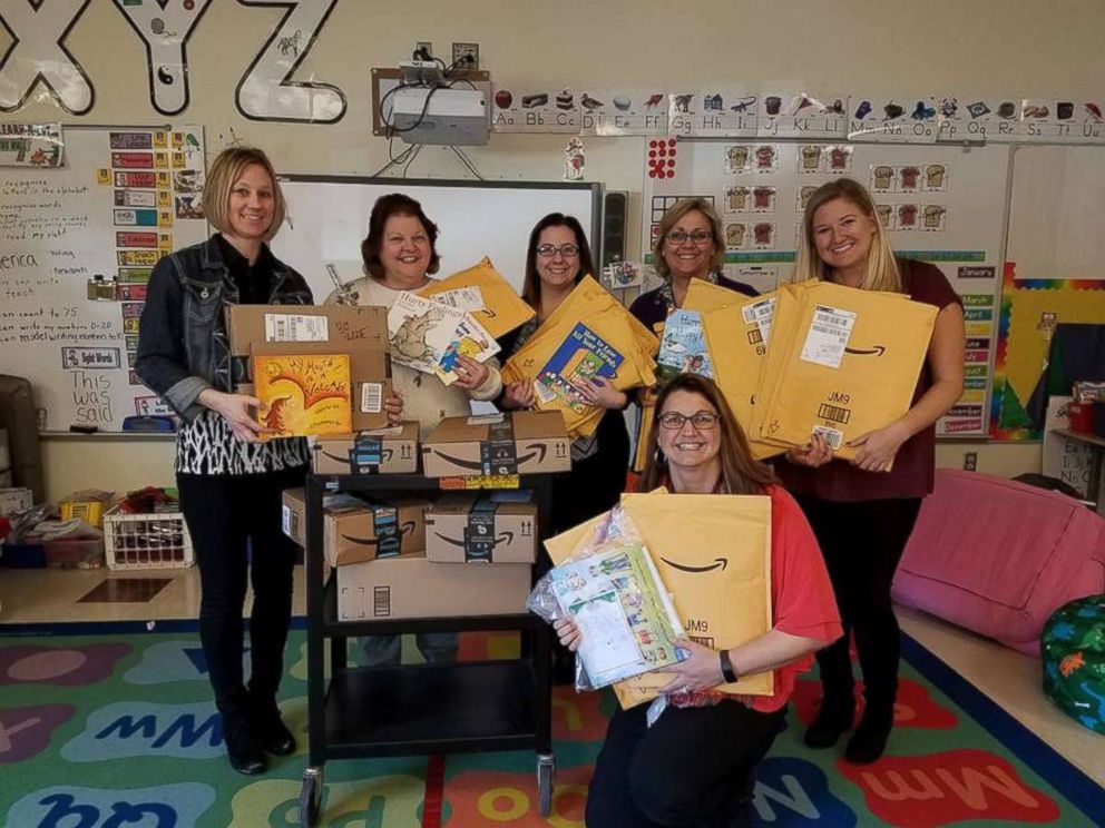 PHOTO: Tina DuBrock, kneeling, poses with fellow teachers holding books delivered to Protsman Elementary School in Dyer, Ind.