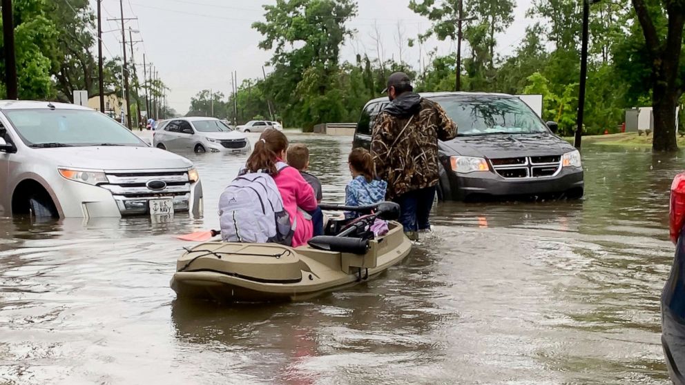 PHOTO: Parents use boats to pick up students from schools after nearly a foot of rain fell in Lake Charles, La., May 17, 2021. 