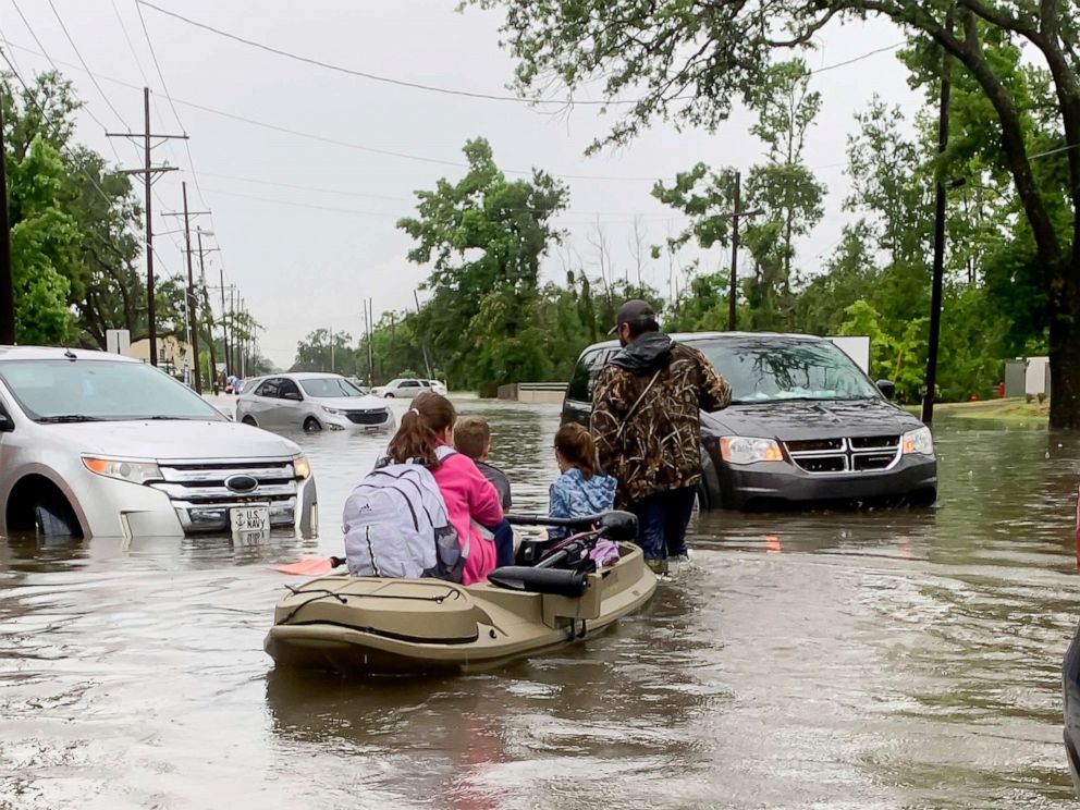 PHOTO: Parents use boats to pick up students from schools after nearly a foot of rain fell in Lake Charles, La., May 17, 2021. 