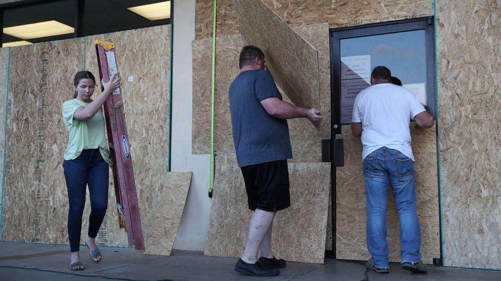 PHOTO: LAKE CHARLES, LOUISIANA- AUGUST 25:   (L-R) Lacey Buller, Tyler Arnold and Mike Buller work on placing plywood over the windows of their business before the arrival of Hurricane Laura on August 25, 2020 in Lake Charles, Louisiana. 
