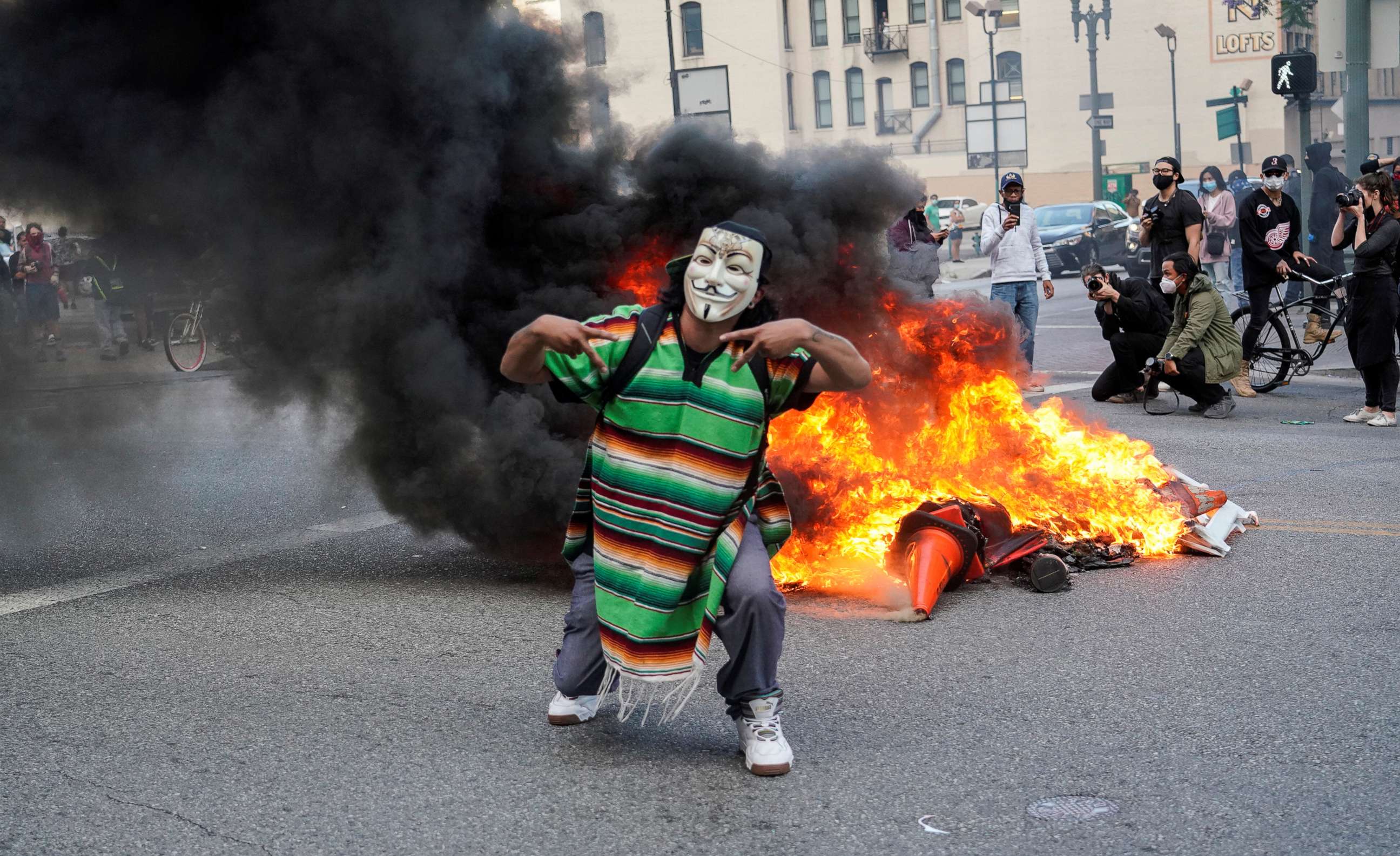 PHOTO: A masked protester stands in front of a fire during a rally against the death in Minneapolis police custody of George Floyd, in Los Angeles, California, U.S., May 30, 2020. Picture taken May 30, 2020.