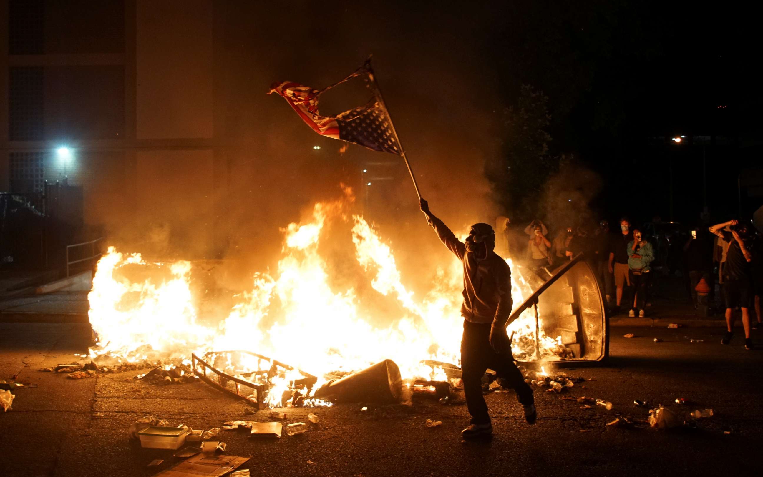 PHOTO: A protestor waves a burned American flag over a fire during a protest against the death in Minneapolis police custody of African-American man George Floyd, in St Louis, Missouri, U.S., June 1, 2020. Picture taken June 1,2020 