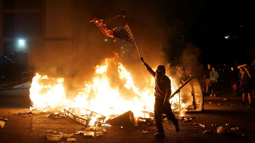 PHOTO: A protestor waves a burned American flag over a fire during a protest against the death in Minneapolis police custody of African-American man George Floyd, in St Louis, Missouri, U.S., June 1, 2020. Picture taken June 1,2020 