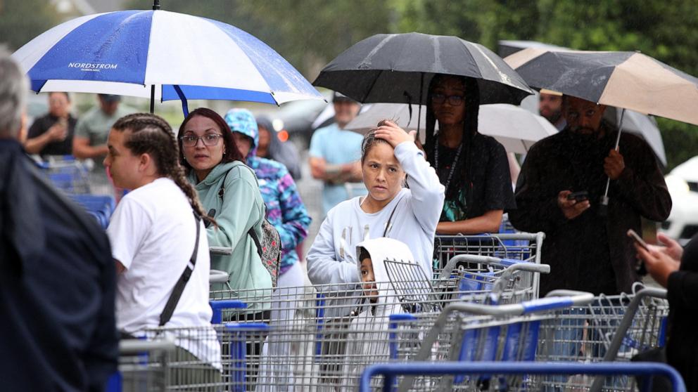 PHOTO: Local residents form a long line in the rain before the opening of a shopping warehouse ahead of Hurricane Milton's expected mid-week landfall in Kissimmee, Fla., Oct. 7, 2024. 