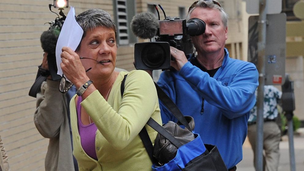 After leaving the Ramsey County Court House, Lori Christensen, left, tries to hide from the media by using a white sheet of paper, May 30, 2012, in St. Paul, Minn.
