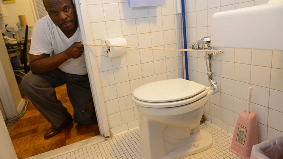 Brooklyn resident Michel Pierre, pictured using a rope to flush his repaired toilet, Oct. 9, 2013.