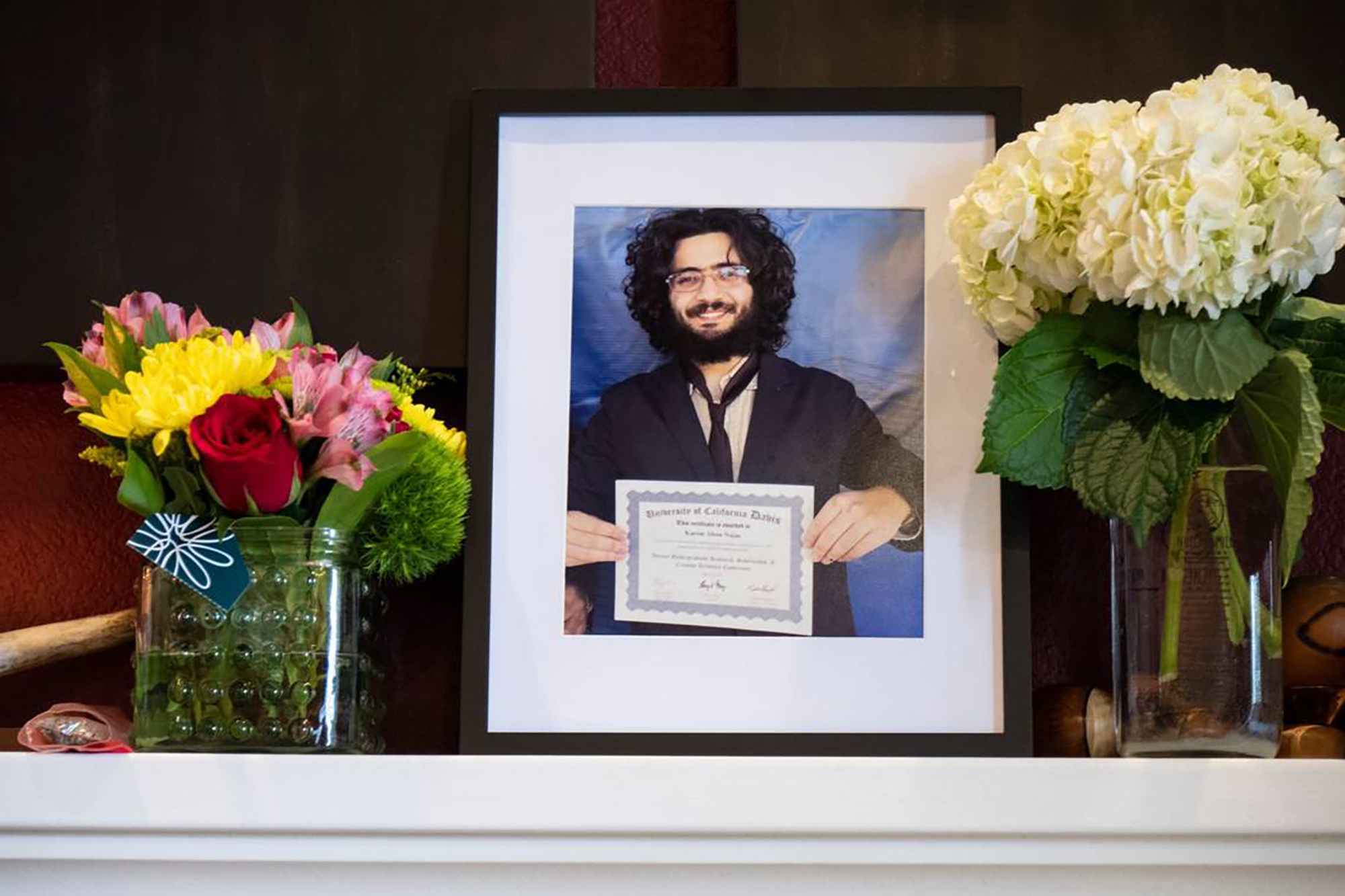 PHOTO: A portrait of Karim Abou Najm stands amid flowers on the fireplace mantel of his family home in Davis, Calif., May 1, 2023.