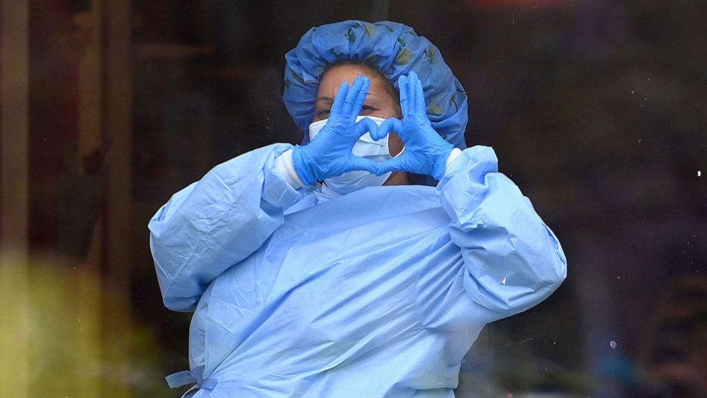 PHOTO: A health care worker makes the shape of a heart with her hands behind a window at Jacobi Medical Center on April 17, 2020 in the Bronx, New York. 