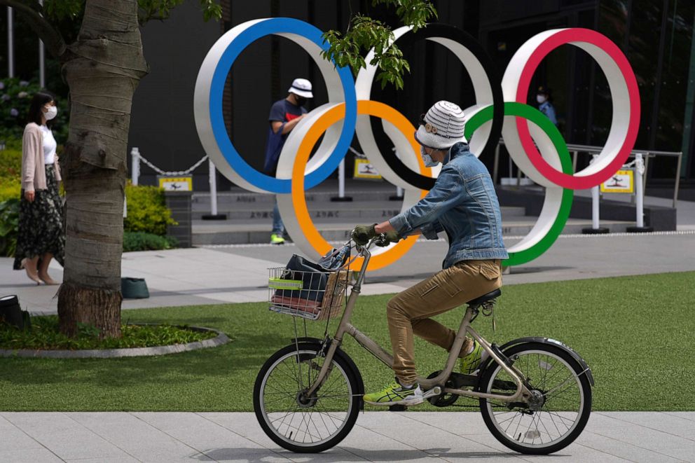 PHOTO: A woman rides a bicycle near the Olympic Rings, June 2, 2021, in Tokyo. 