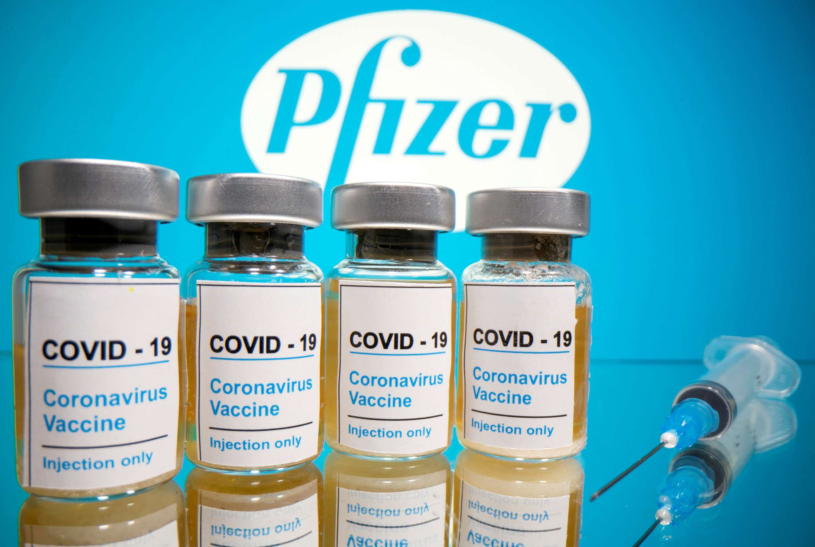 FILE PHOTO: Vials with a sticker reading, "COVID-19 / Coronavirus vaccine / Injection only" and a medical syringe are seen in front of a displayed Pfizer logo in this illustration taken October 31, 2020. 