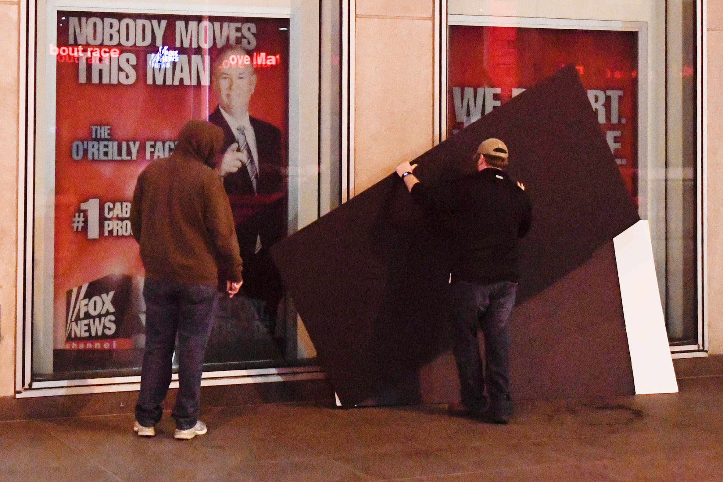 PHOTO: Men place boards over a poster of former cable news host Bill O'Reilly outside of the Fox News offices in Manhattan, April 20, 2017.