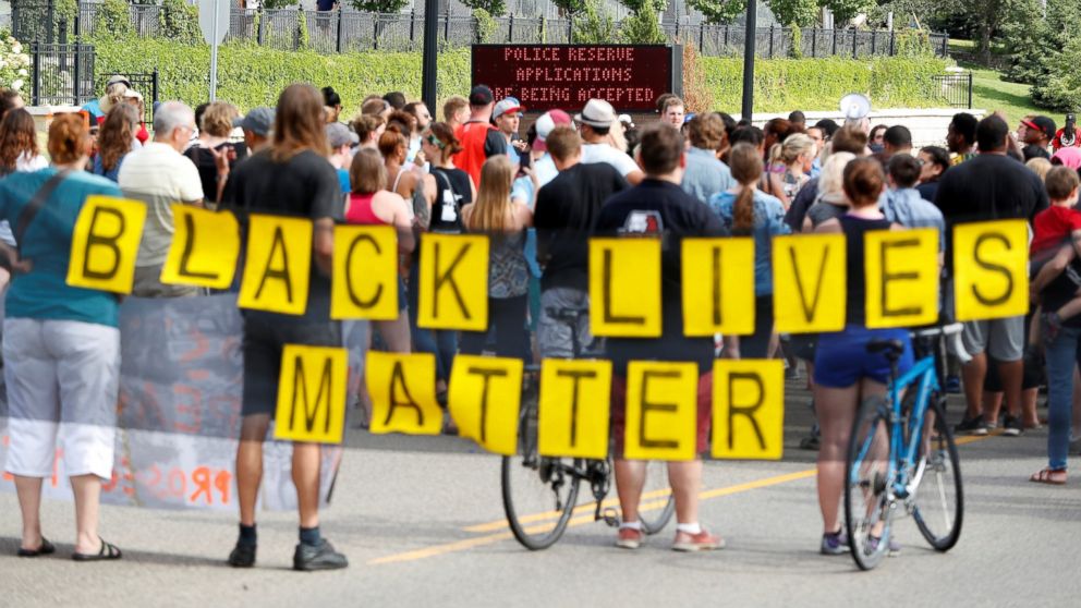 Demonstrators carry a "Black Lives Matter" banner and protest the shooting death of Philando Castile as they gather in front of the police department in St Anthony, Minnesota, U.S., July 10, 2016.