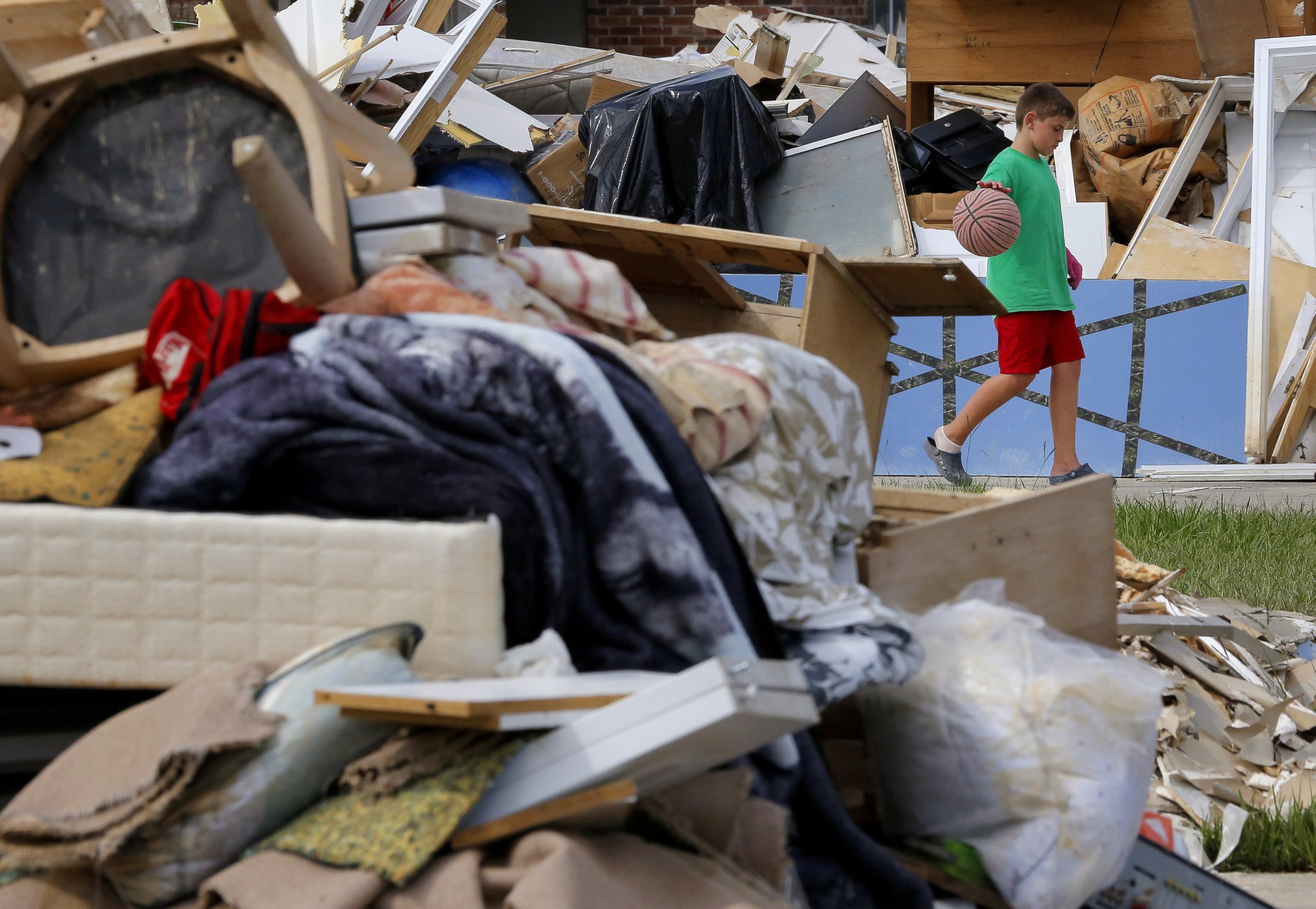 PHOTO: Noah Slayton, 9, dribbles a basketball in between piles of debris in front of his flood damaged home at the South Point subdivision in Denham Springs, Louisiana, Aug. 22, 2016.  