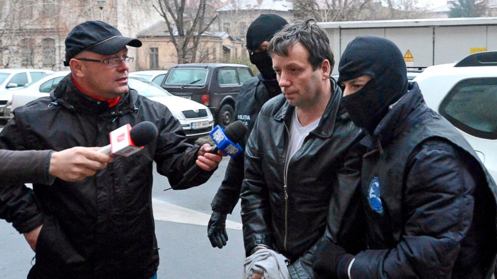 Marcel Lazar Lehel, 40, is escorted by masked policemen in Bucharest, after being arrested in Arad, on Jan. 22, 2014. 