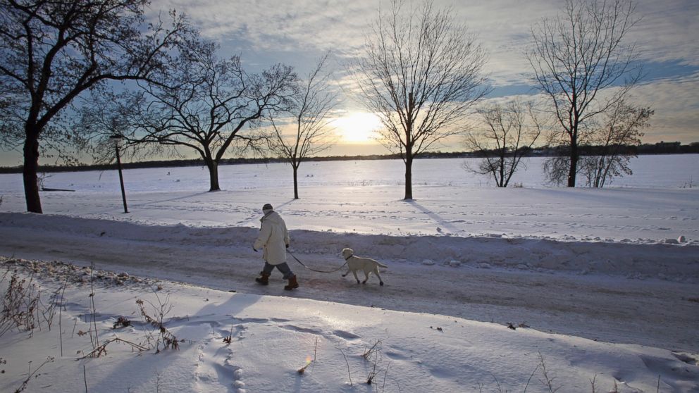 A woman walks her dog as the sun goes down along Lake Calhoun in Minneapolis, Jan. 7, 2014. 