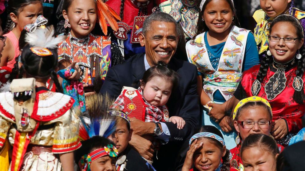 PHOTO: Barack Obama holds a baby as he poses with children at the Cannon Ball Flag Day Celebration at the Cannon Ball Powwow Grounds on the Standing Rock Sioux Reservation in North Dakota, June 13, 2014. 