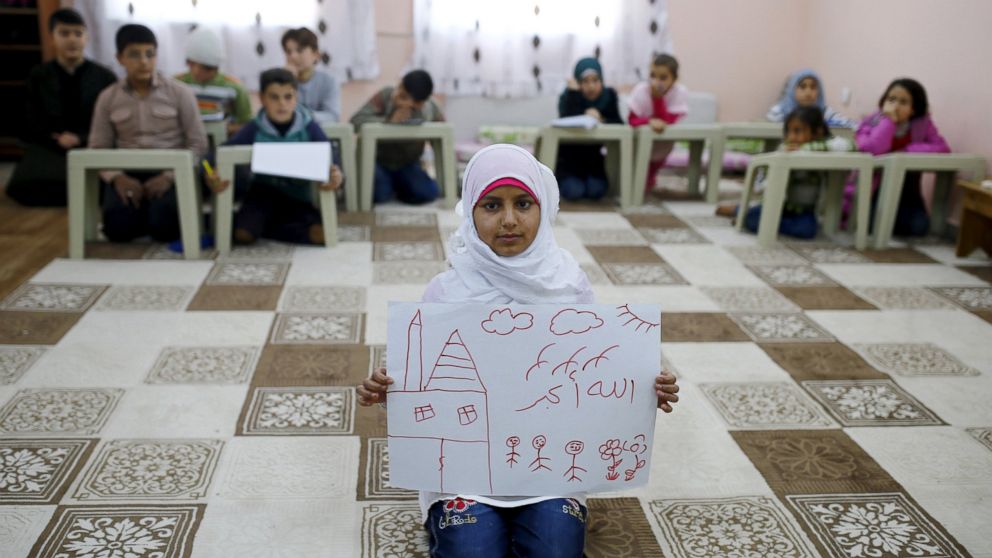 Syrian refugee Islem Halife, 11, shows a drawing of her home in Syria, as she sits in a classroom where she learns the Quran in Nizip refugee camp in Gaziantep province, Turkey on Dec. 13, 2015. The writing in Arabic in the drawing reads, "God is great."