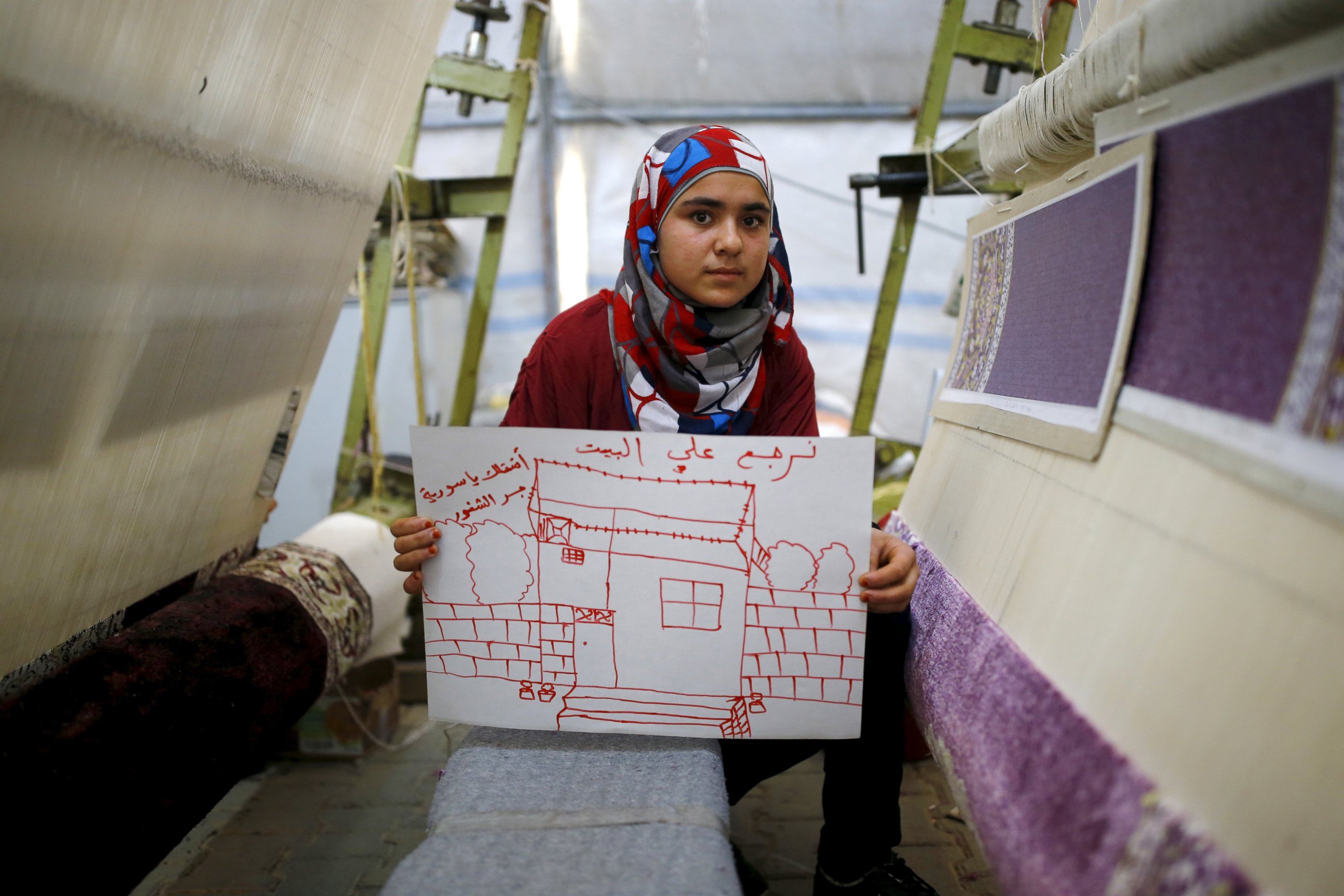 PHOTO: Syrian refugee Meryem Mahmo, 14, shows a drawing of her home during a carpet weaving workshop in Midyat refugee camp in Mardin province, Turkey, Dec. 14, 2015. The Arabic writing on the picture reads: "I want my home. I miss you Syria." 