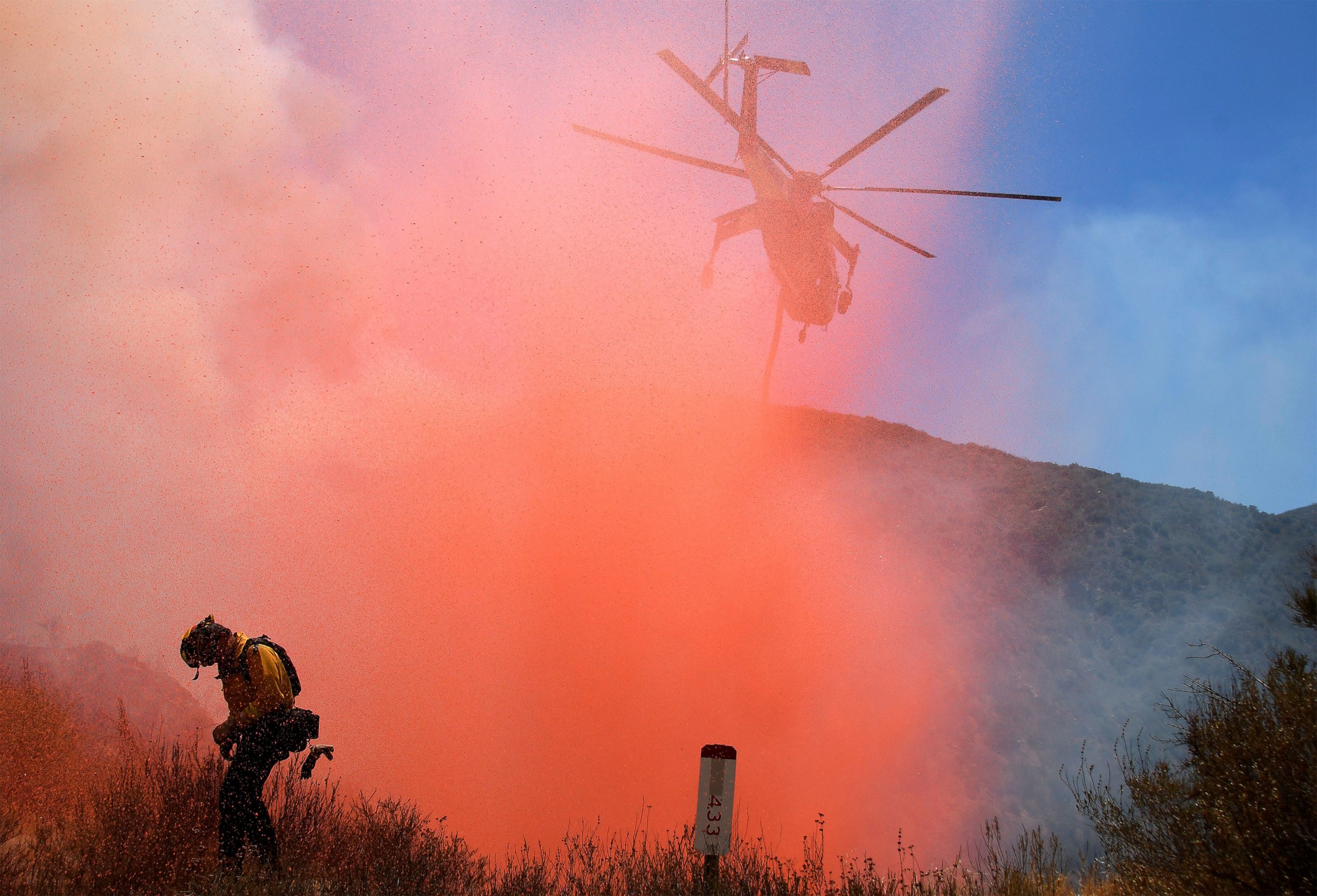 PHOTO: A fire fighter is sprayed with retardant as a helicopter makes a drop as emergency workers continue to battle fire in the Angeles National Forest near Los Angeles, California, July 25, 2016.