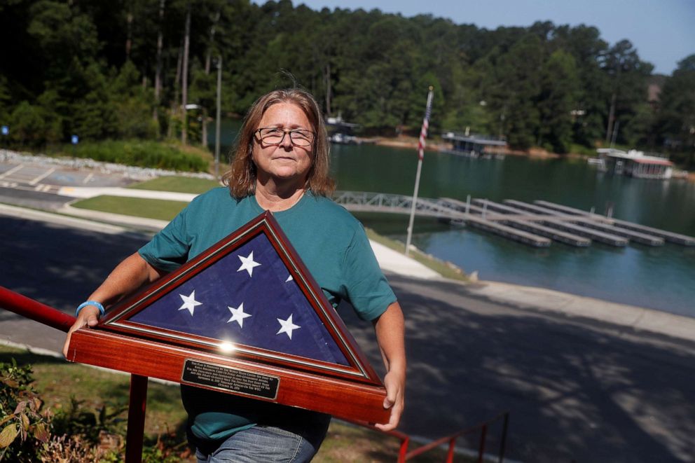 PHOTO: Kayla Bergeron, who worked for the Port Authority of New York and New Jersey during the 9-11 attacks on the World Trade Center, poses with a framed U.S. flag given to her by the agency at Lake Lanier in Cumming, Ga., July 4, 2021.
