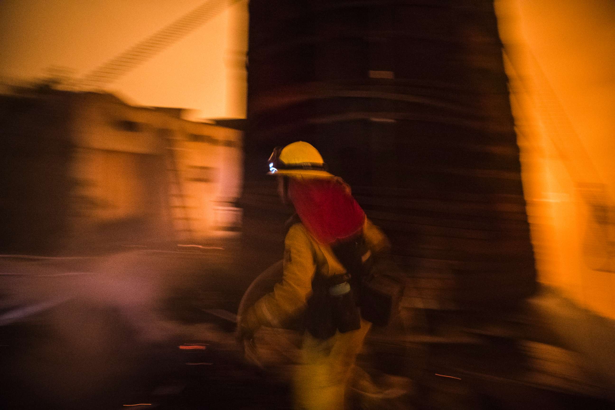 PHOTO: A Cal Fire firefighter races to protect a structure in upper Toro Canyon, Calif. on Dec. 11, 2017. The home was saved but the water tank burned down the next morning due to a constant flow of embers. 