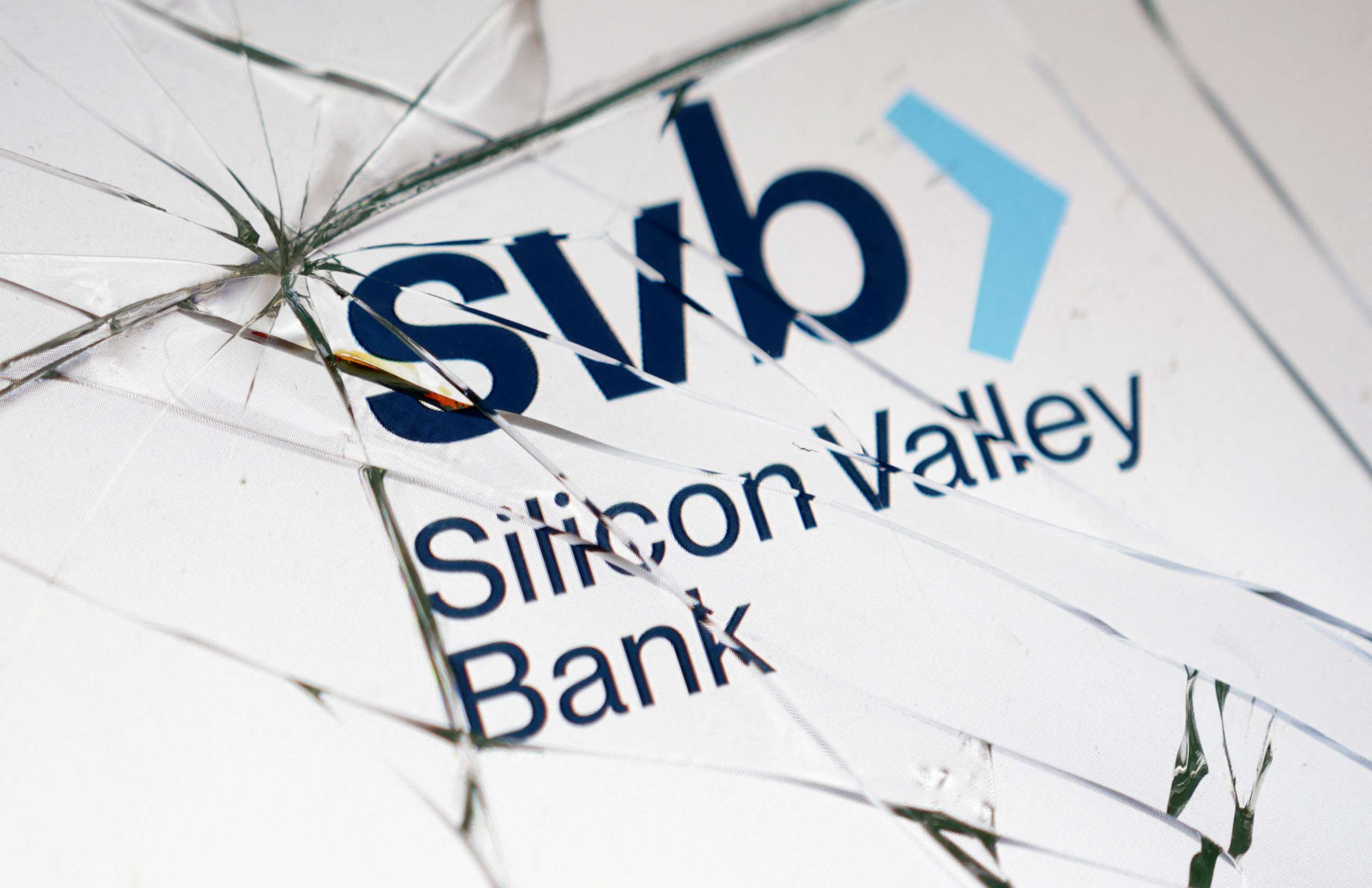 PHOTO: Silicon Valley Bank (SVB) logo is seen through broken glass in this picture illustration taken March 16, 2023.