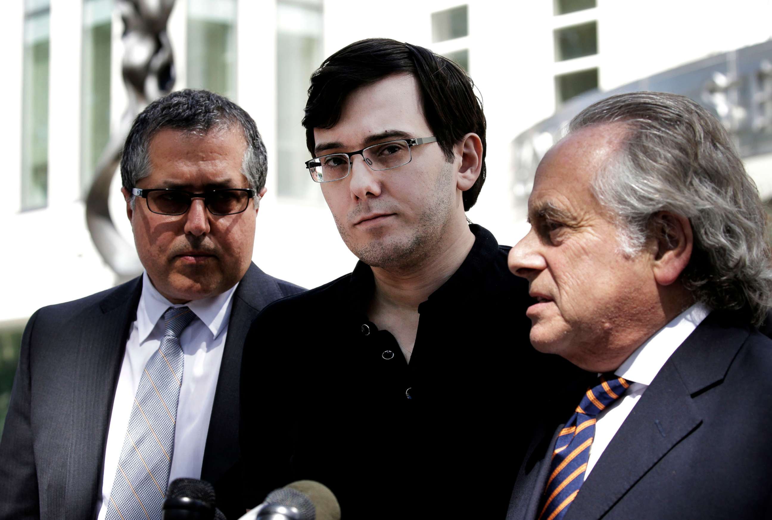 PHOTO: Martin Shkreli, former chief executive officer of Turing Pharmaceuticals AG, center, listens while his attorney Benjamin Brafman, right, speak to members of the media outside federal court in Brooklyn, N.Y., Aug. 4, 2017.