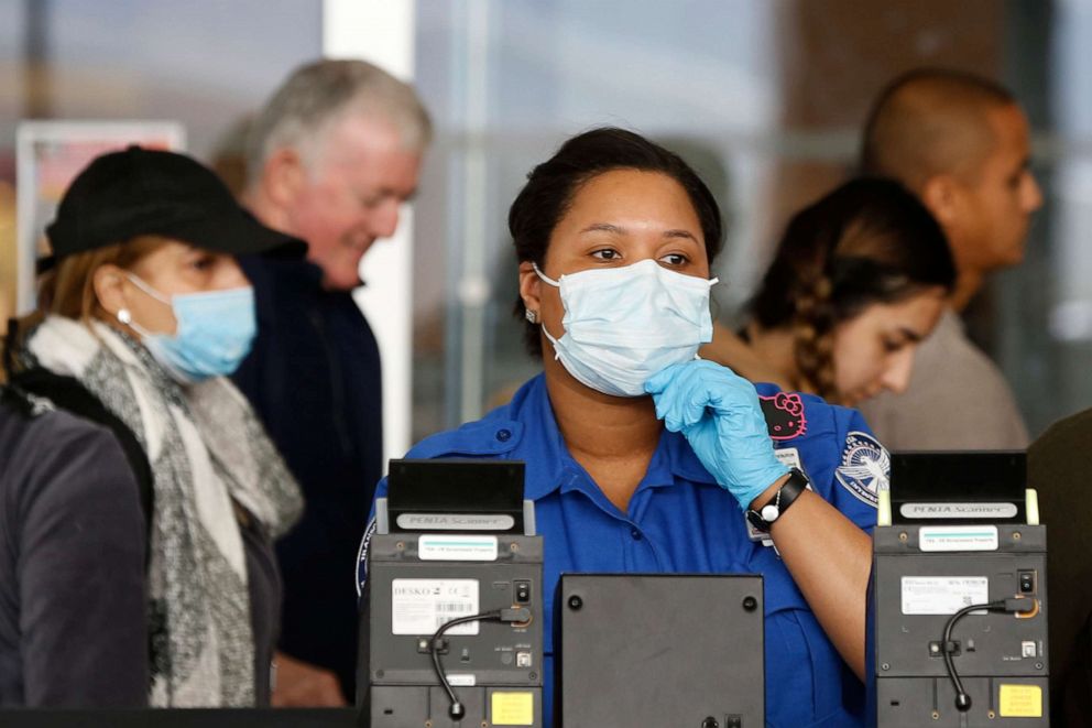 PHOTO: A Transportation Security Administration (TSA) employee adjusts her face mask while screening passengers entering through a checkpoint at John F. Kennedy International Airport, Saturday, March 14, 2020, in New York. 