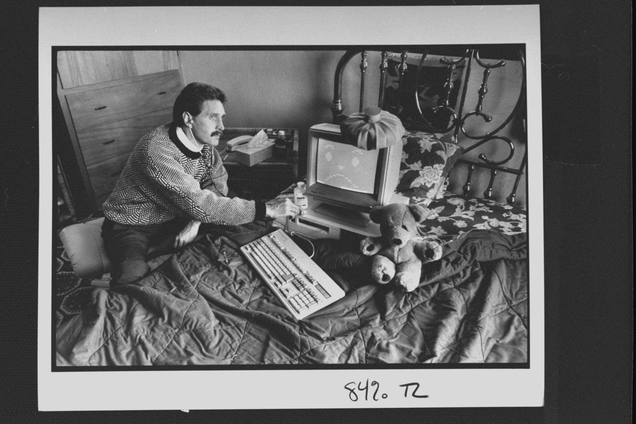 PHOTO: Computer analyst John McAfee holding stethoscope to IBM type computer sitting on bed w. ice bag on top, illustrating computer virus which McAfee is able to eradicate; at home.