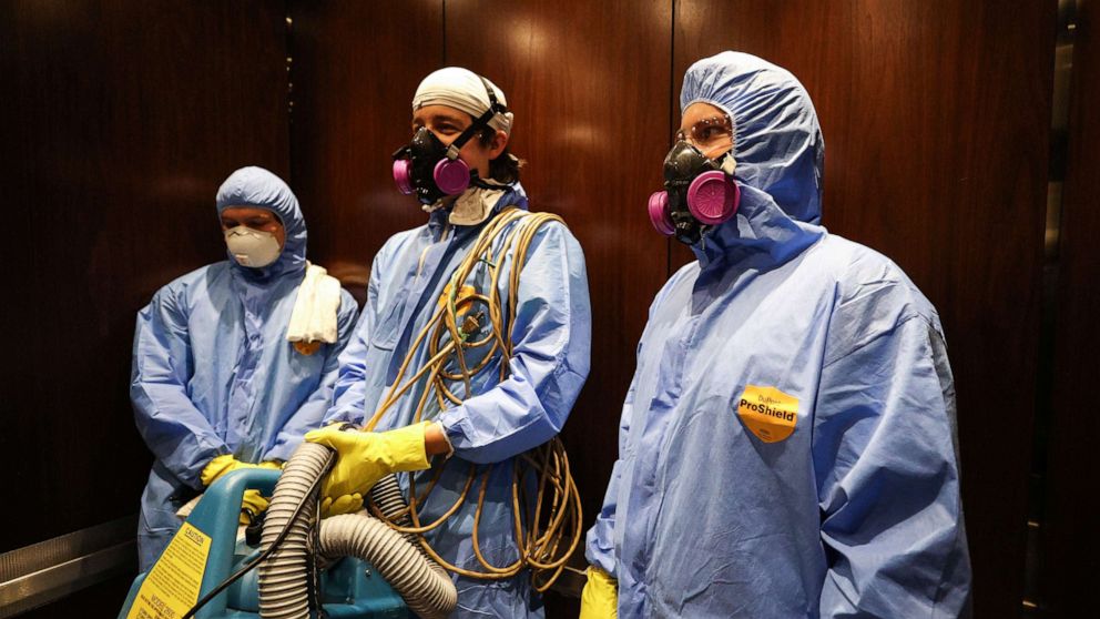 PHOTO: Maryland Cleaning and Abatement Services employees Graham Sevy (L), Bob Wiglesworth, (C) and Alec Pine (R) ride in an elevator before preforming a preventative fogging and damp wipe treatment on March 21, 2020 in Hunt Valley, Maryland. 