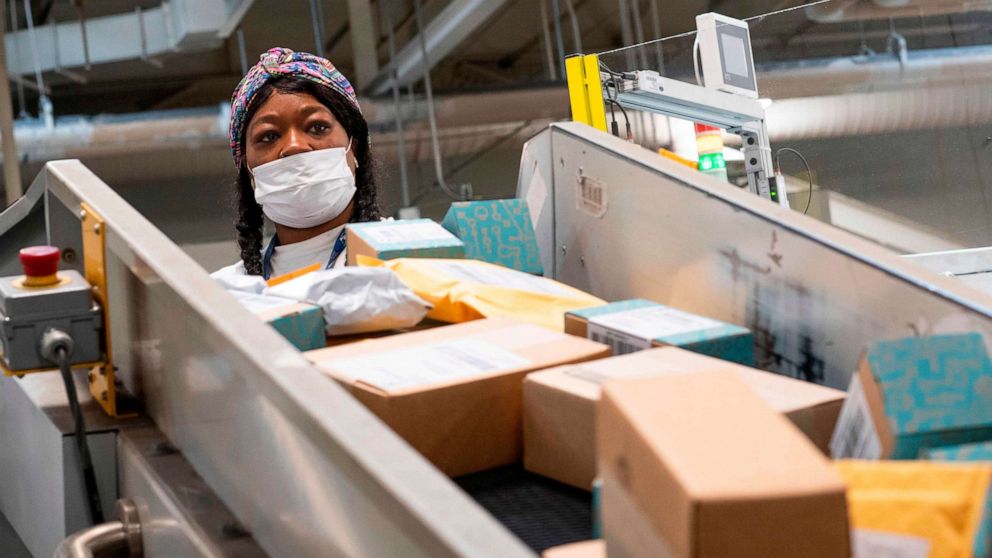 PHOTO: (FILES) In this file photo taken on April 30, 2020, a postal worker sort mail at a Los Angeles, California, facility.