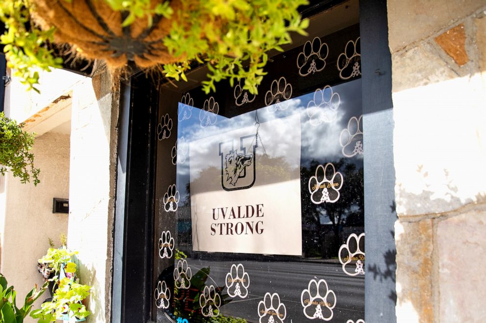 PHOTO: A sign with the "Uvalde Strong" message and a Uvalde High School Coyote logo is displayed on the window of a building in downtown Uvalde, Texas, on Aug. 21, 2022.
