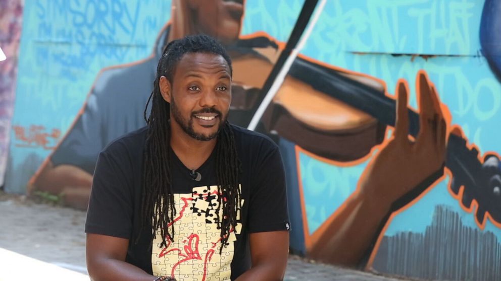 PHOTO: New York City-based artists Vince Ballentine talks to "Nightline" in front of a mural of Elijah McClain, which he painted in July 2020. 