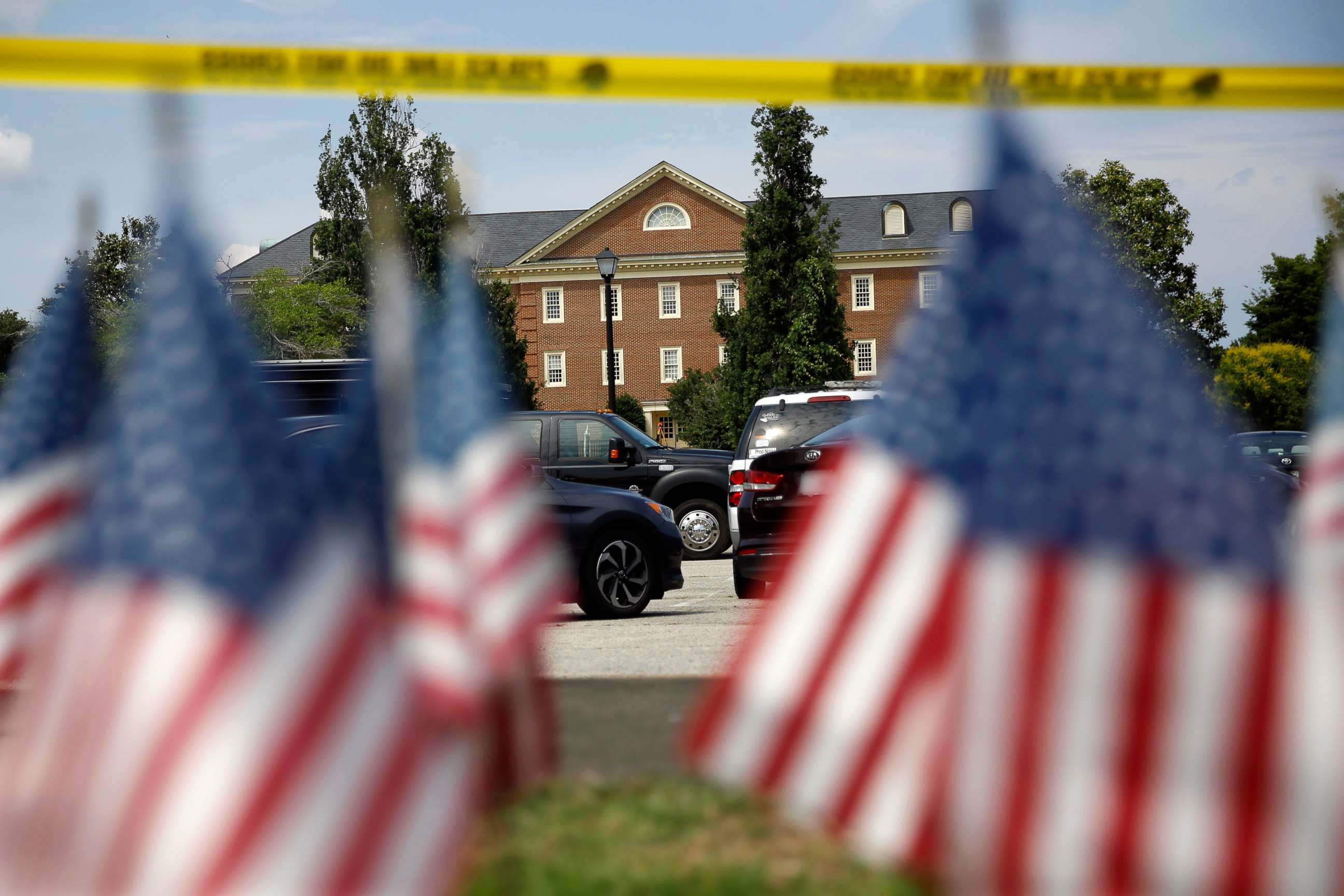 PHOTO: American flags that are part of a makeshift memorial stand at the edge of a police cordon in front of a municipal building that was the scene of a shooting, June 1, 2019, in Virginia Beach, Va. 