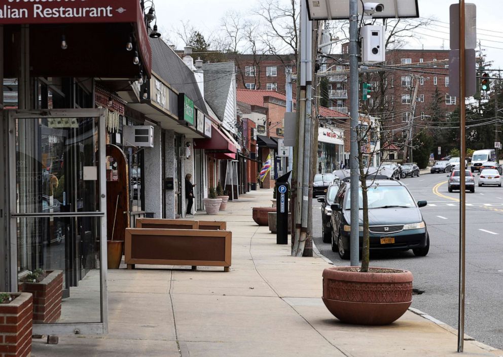 PHOTO: A solitary woman checks her cellphone on a normally busy North Avenue inside what's called a "containment area" in New Rochelle, N.Y., Wednesday, March 11, 2020. State officials on Tuesday called for closing schools and houses of worship.