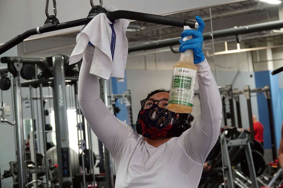 PHOTO: Adriana Laplanche disinfects her station during a weighlifting workout at the Palm Beach Gym in Boca Raton, Monday, May 18, 2020. Gyms in South Florida were allowed to reopen with precautions. 